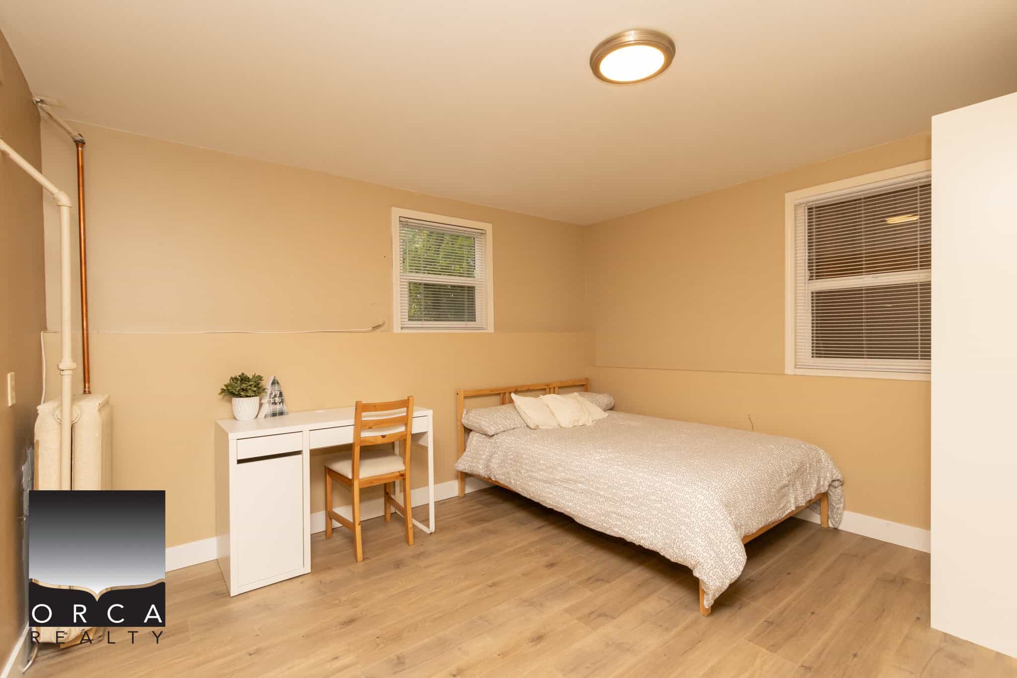 Bright and cozy bedroom in Vancouver property listed by Orca Realty Inc., featuring neutral decor, hardwood flooring, and natural light from double-pane windows, ideal for comfortable living.