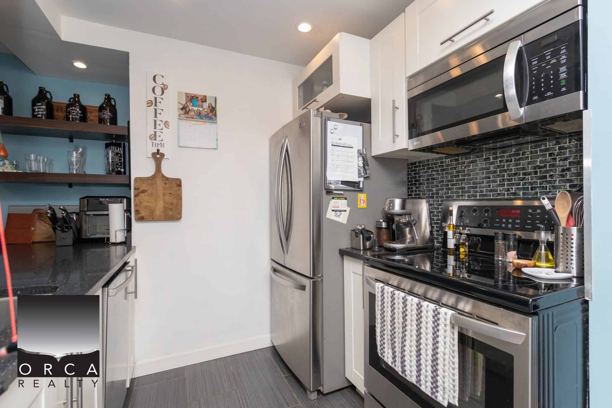 Modern stainless steel appliances in a contemporary kitchen at Orca Realty Inc., showcasing a sleek black backsplash, bright white cabinetry, and stylish decor, perfect for Vancouver real estate.