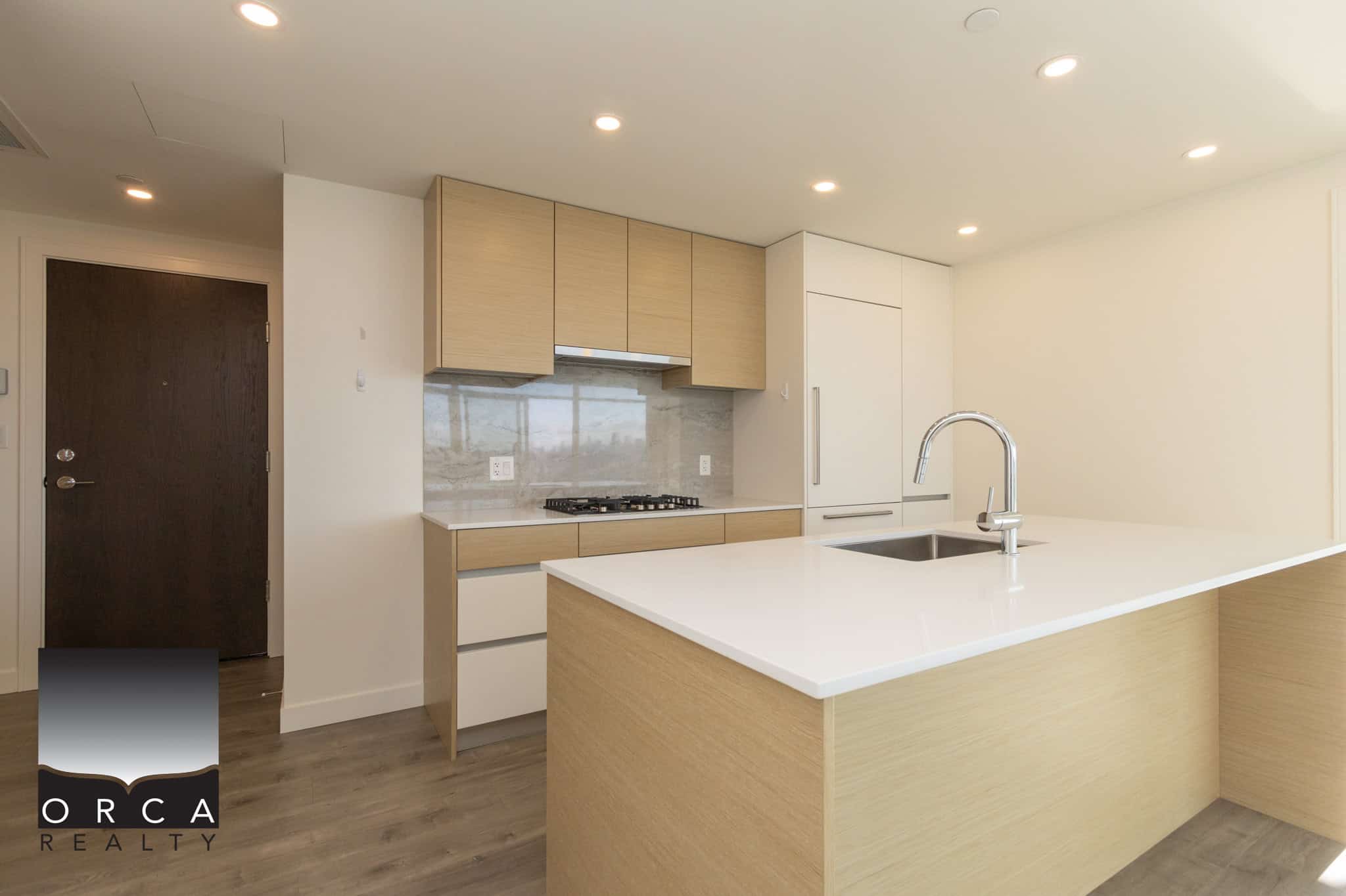 Modern open-concept kitchen featuring minimalist cabinetry, sleek white countertops, and contemporary design, ideal for Vancouver Island real estate listings and homebuyers.