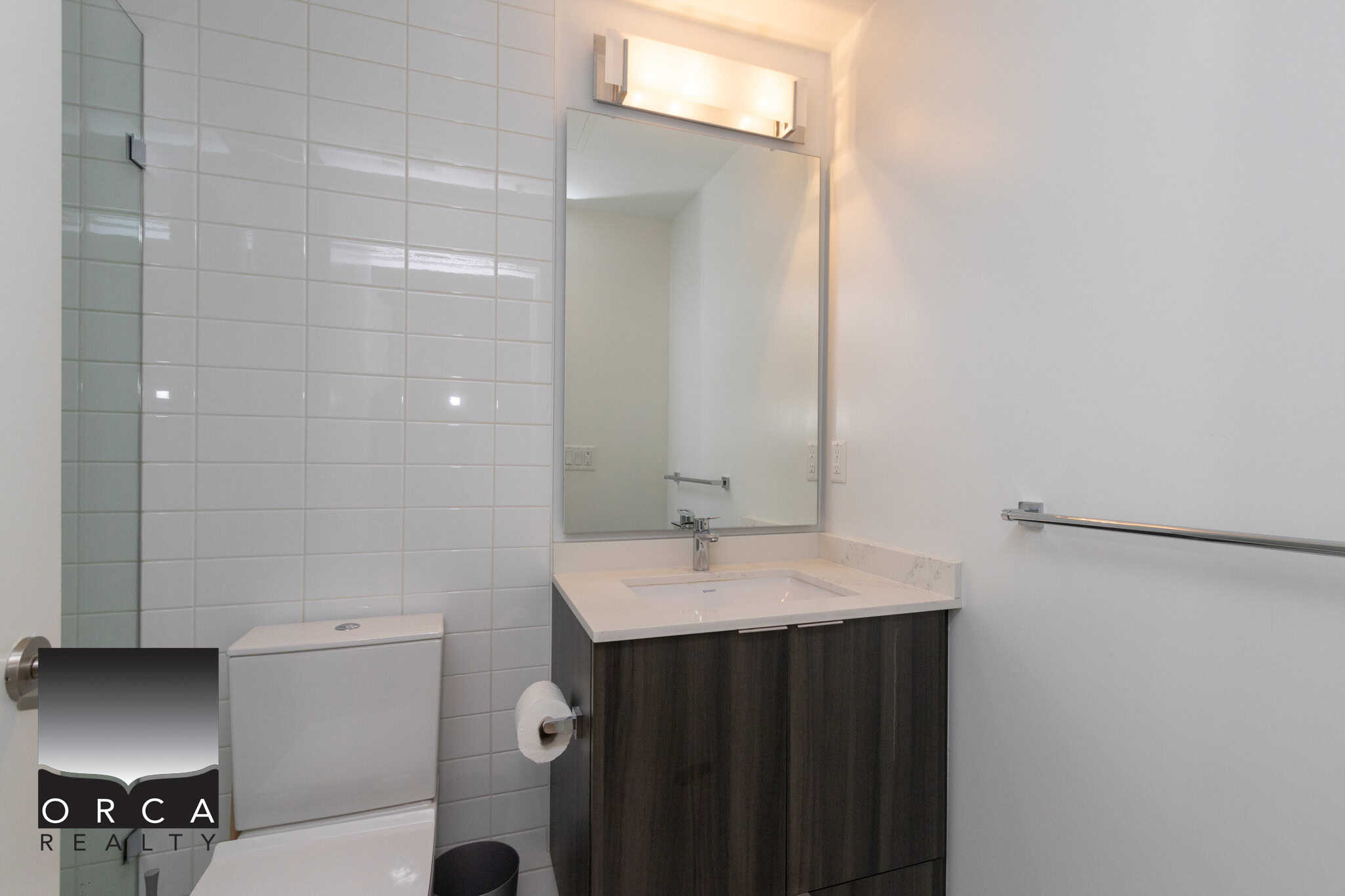Modern bathroom with white tile wall, sleek vanity, and contemporary lighting, ideal for Vancouver real estate listings and property marketing by Orca Realty Inc.