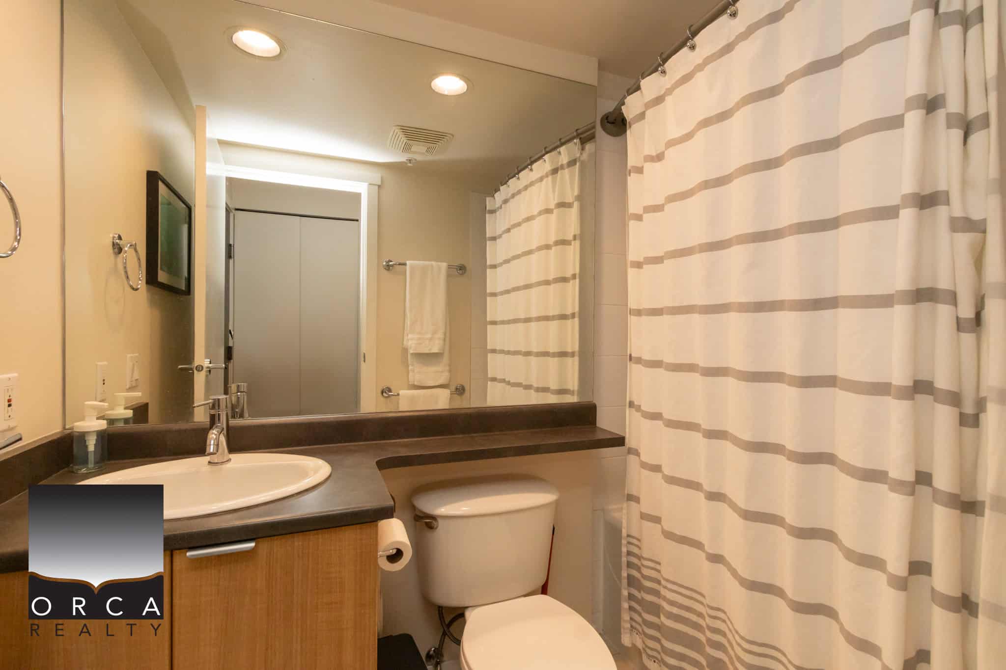 Modern bathroom with neutral colour scheme, shower curtain, and contemporary fixtures showcasing available properties with Orca Realty Inc.