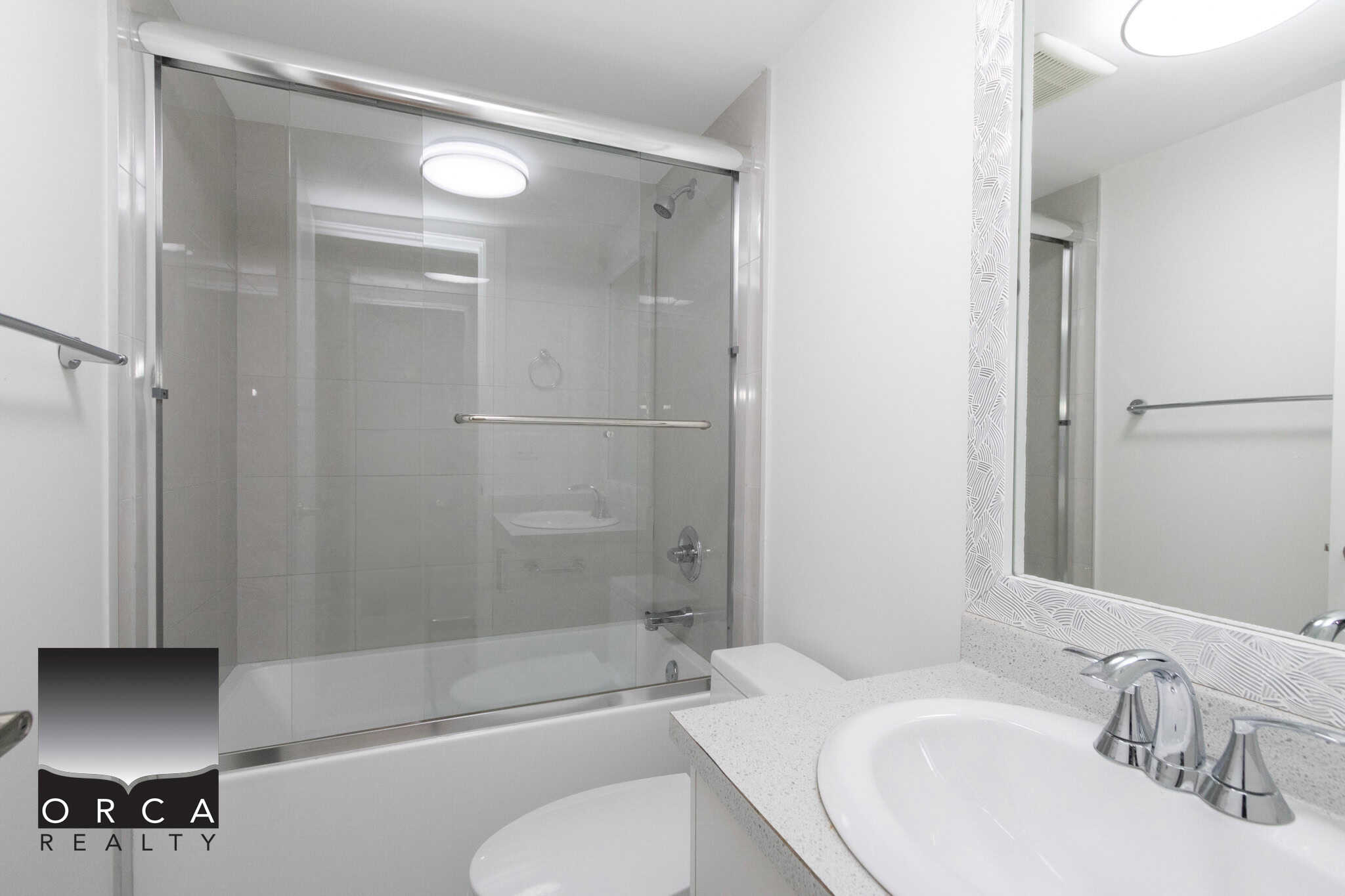 Modern bathroom with glass-enclosed shower and sleek vanity, part of Orca Realty Inc. listings, showcasing stylish and affordable real estate options in safe and desirable neighborhoods.