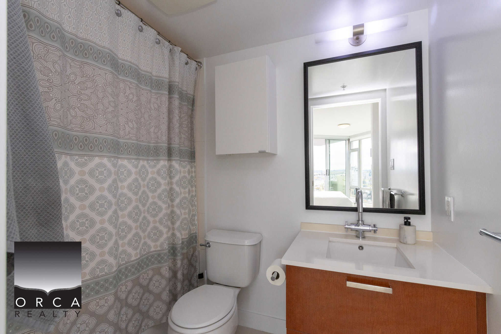 Bright modern bathroom with white walls, wooden vanity, large mirror, and shower curtain, showcasing interior design ideal for Vancouver condos and real estate listings.