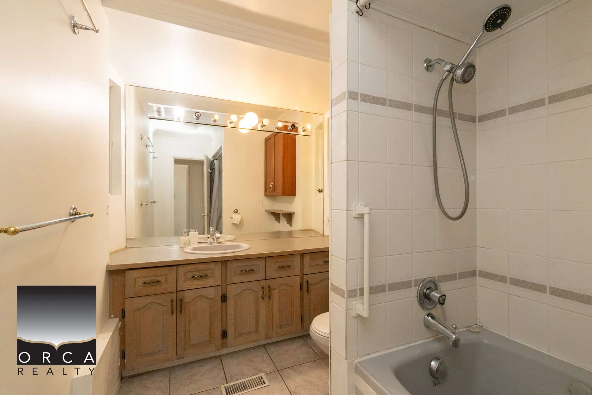 9 copy Bright bathroom with large mirror, wooden vanity, and a tub/shower combo featuring beige tile walls, ideal for Vancouver Island homebuyers.