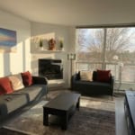 Cozy living room with modern furniture, large windows offering natural light and views, fireplace, and contemporary decor, perfect for enjoying the beautiful surroundings in Vancouver.