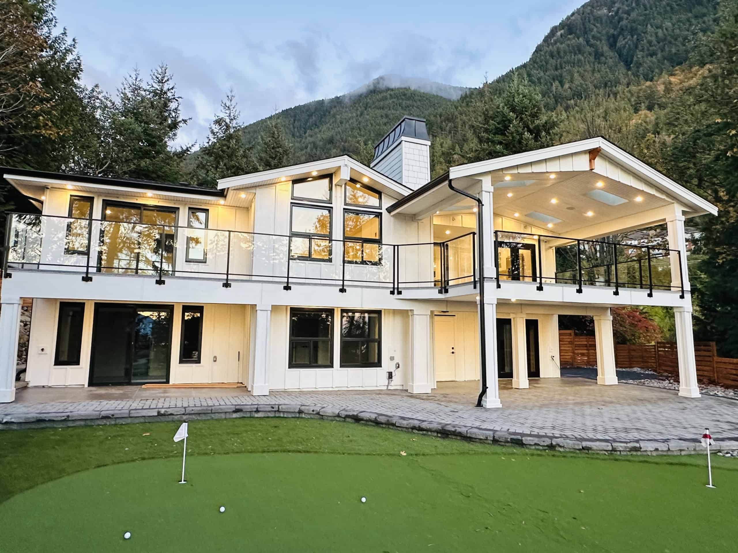 Luxurious modern home with mountain views, spacious balconies, and a manicured lawn, ideal for real estate opportunities in Vancouver and surrounding BC areas.