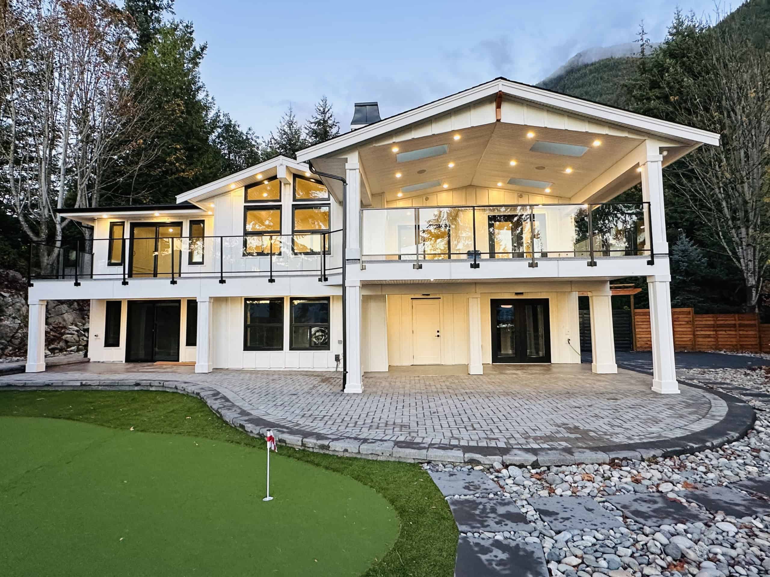 Modern luxury home with expansive outdoor deck, large windows, and scenic mountain views, ideal for real estate investments and residential living in BC's beautiful landscape.