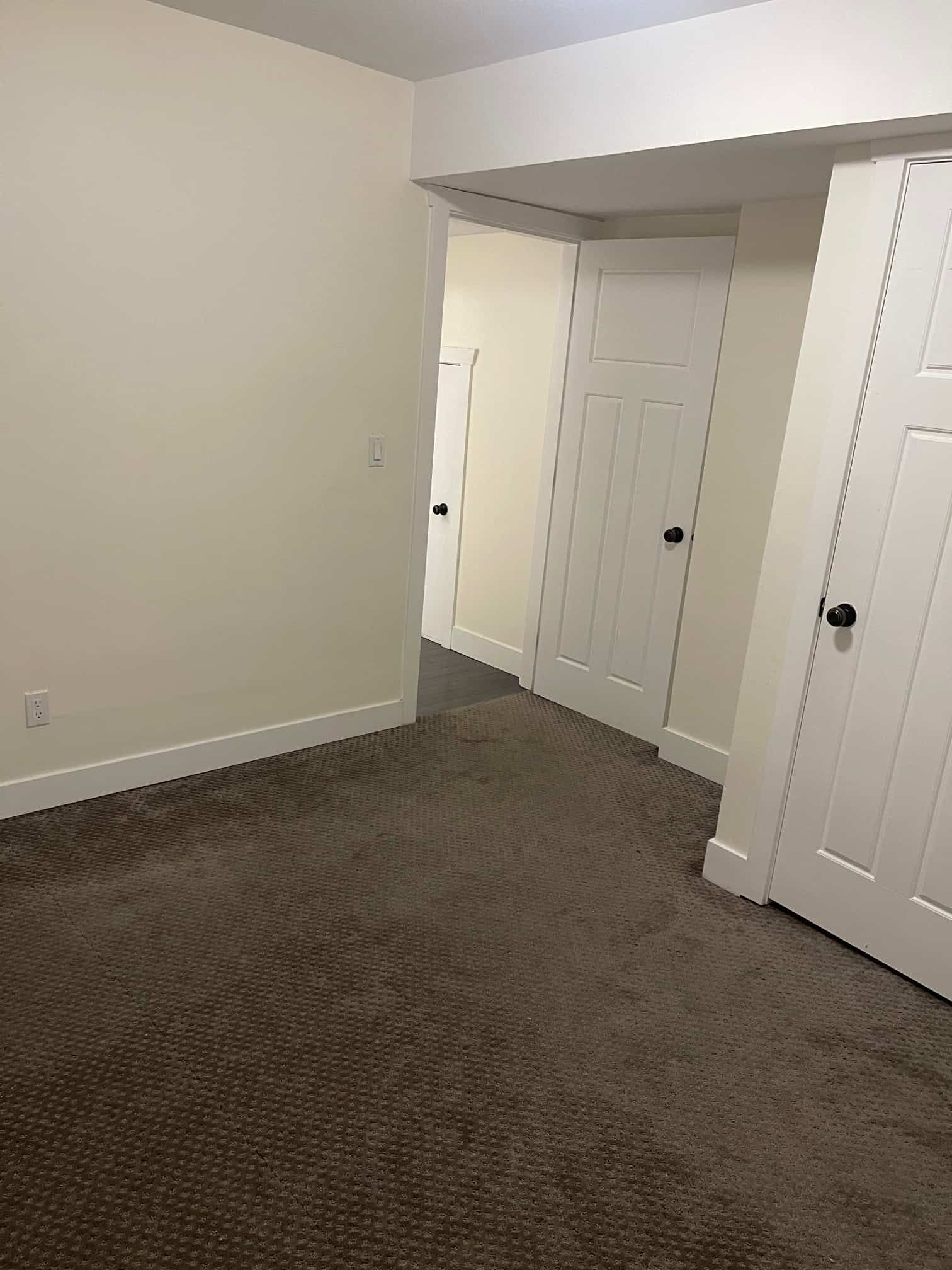 Bright bedroom with neutral wall color, closet doors, and plush brown carpet, ideal for comfortable living in Vancouver area.