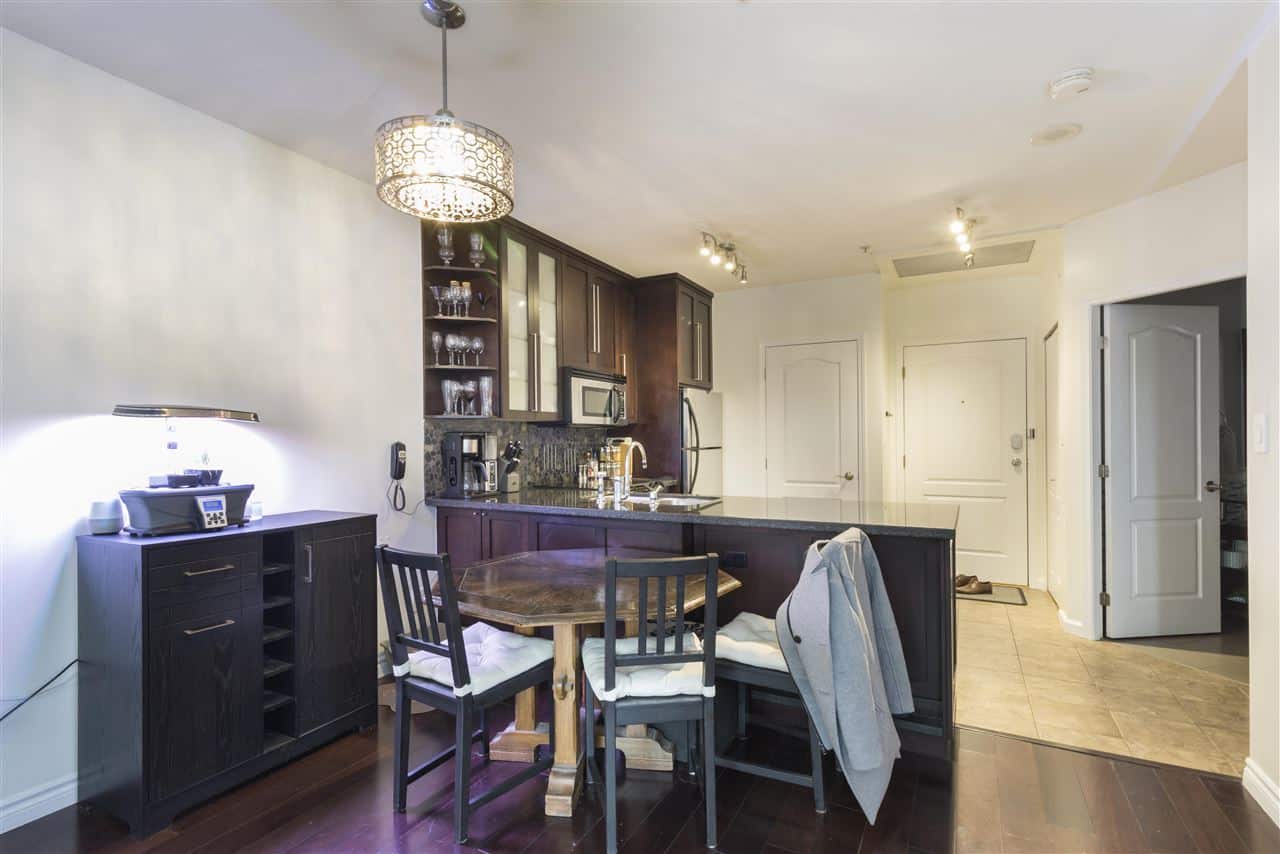 Modern kitchen with dark wooden cabinetry, granite countertops, and contemporary appliances in a Vancouver home. Perfect for family living and entertaining.