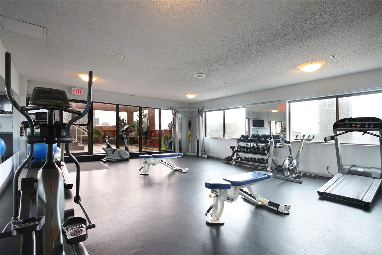 Modern gym and fitness centre with cardio and strength training equipment at Orca Realty Inc. featuring free weights, treadmills, exercise bikes, and fitness benches in a bright, spacious setting.