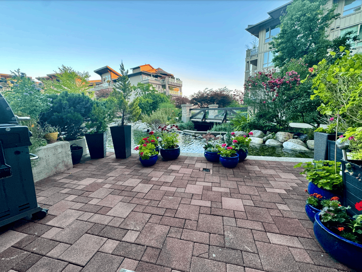 Serene backyard with potted plants and a pond, perfect for relaxation and outdoor entertaining, featured by Orca Realty Inc. in Victoria, BC.