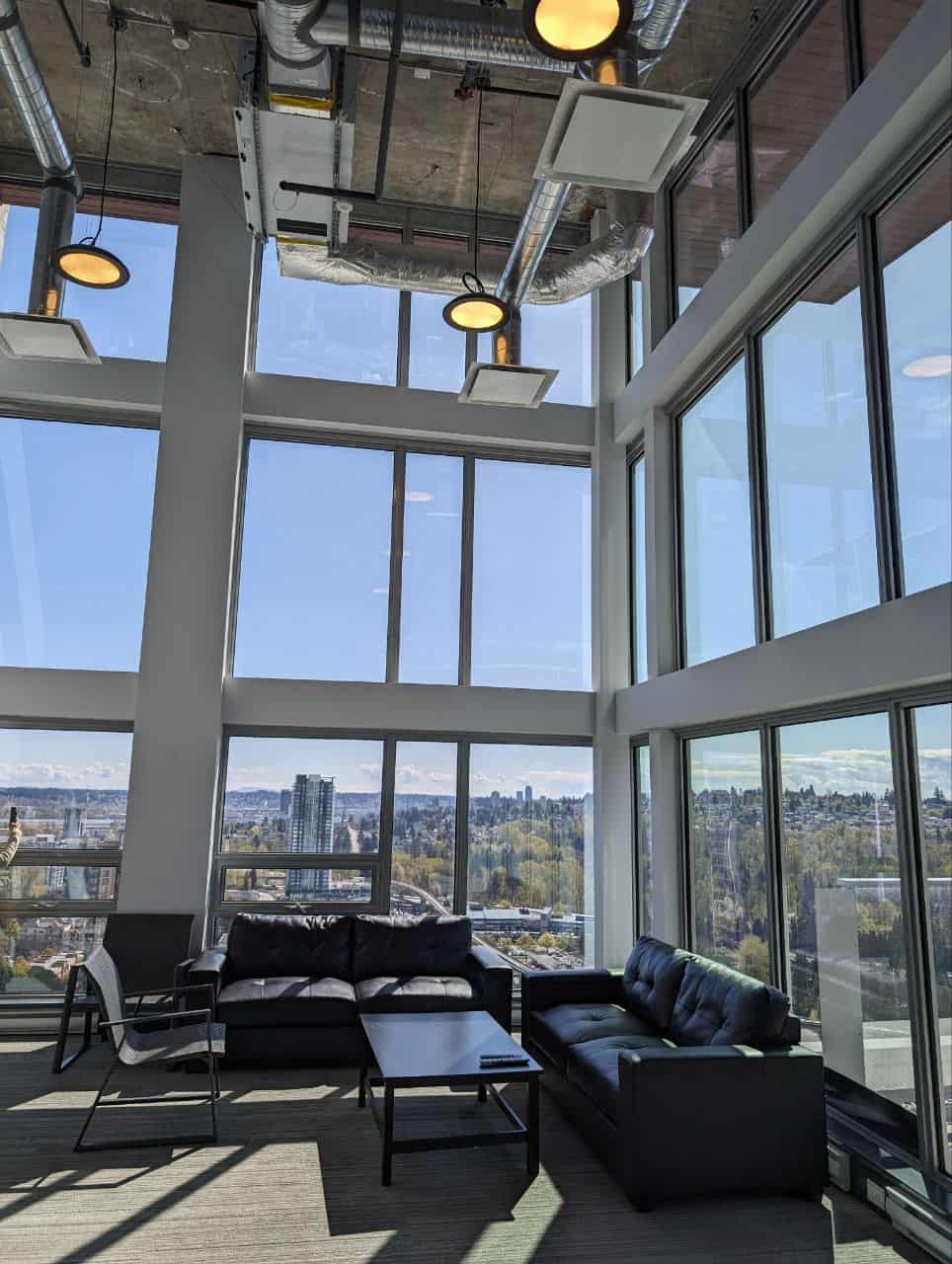 Modern open-concept office space with floor-to-ceiling windows overlooking a cityscape, part of Orca Realty Inc. offerings in Vancouver's commercial real estate market.