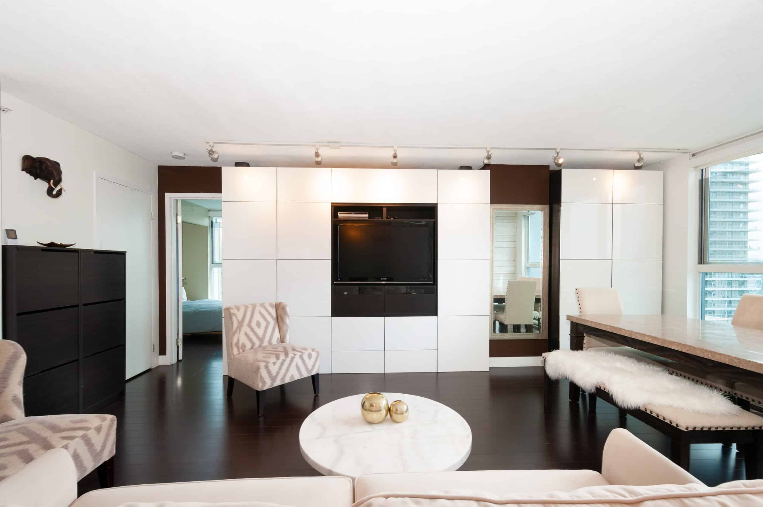 006 Luxurious modern living room with built-in TV wall, contemporary furniture, dark hardwood floors, and large windows providing natural light, ideal for Toronto real estate showcasing.