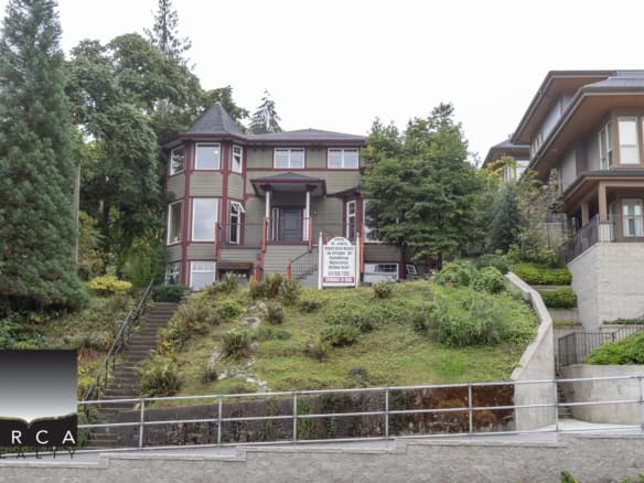 Elegant Victorian-style house on a hillside in Vancouver with lush landscaping, large windows, and a steep front garden, demonstrating premium real estate offerings by Orca Realty Inc.