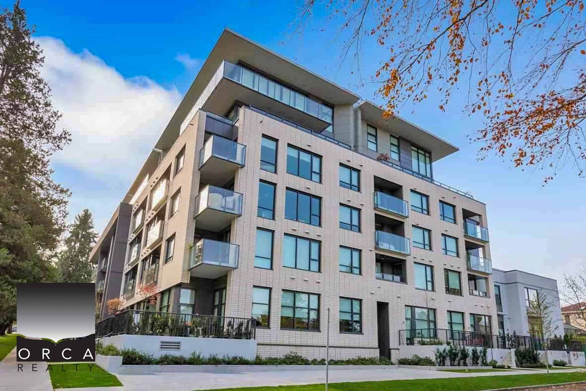 Modern multi-family residential building with large glass windows and balconies, located in a scenic area with trees, showcasing contemporary architecture by Orca Realty Inc.