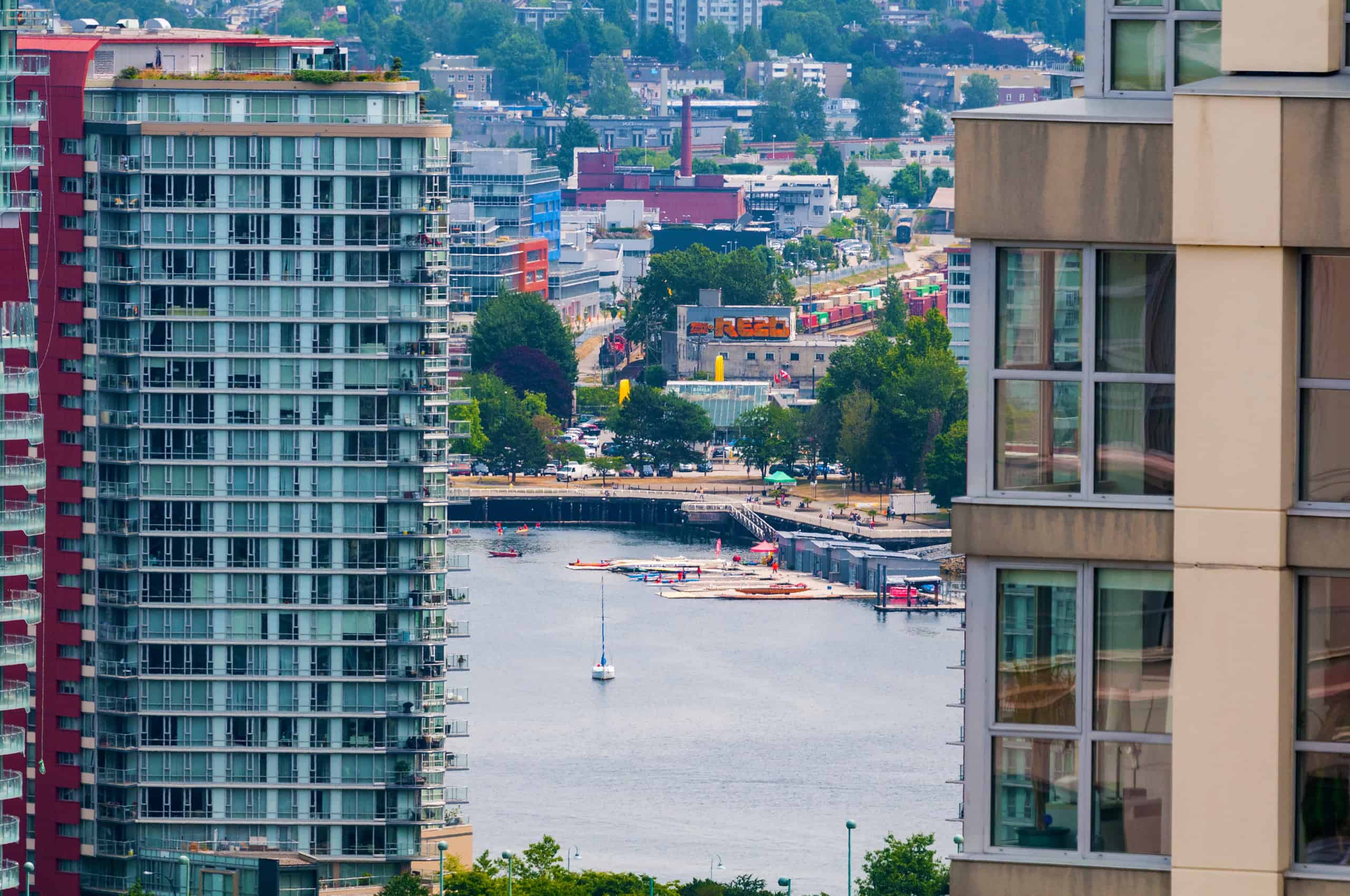 034 Panoramic view of a city skyline featuring modern high-rise condominiums overlooking a marina with boats and kayaks in Vancouver, BC.