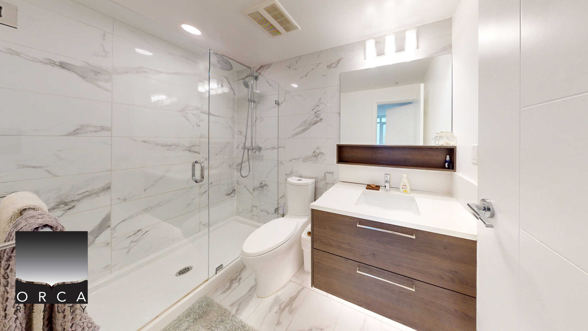 Spacious modern bathroom with marble tile walls, glass shower enclosure, and contemporary vanity, perfect for luxury living and real estate listings in Vancouver.