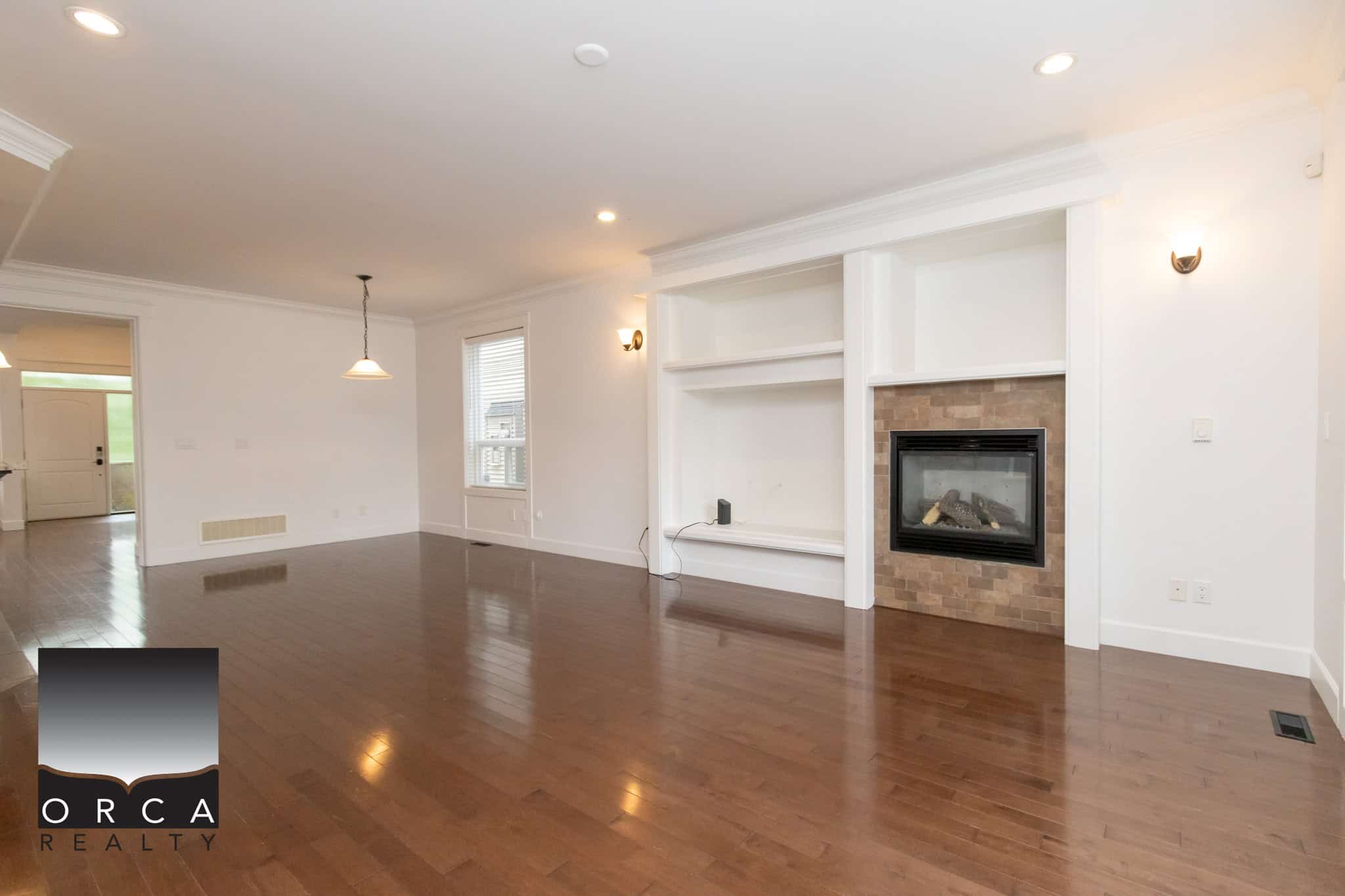 Spacious living room with hardwood flooring, fireplace, and large windows, ideal for family gatherings and relaxation. Modern interior design with white walls and elegant accents in a family-friendly home.