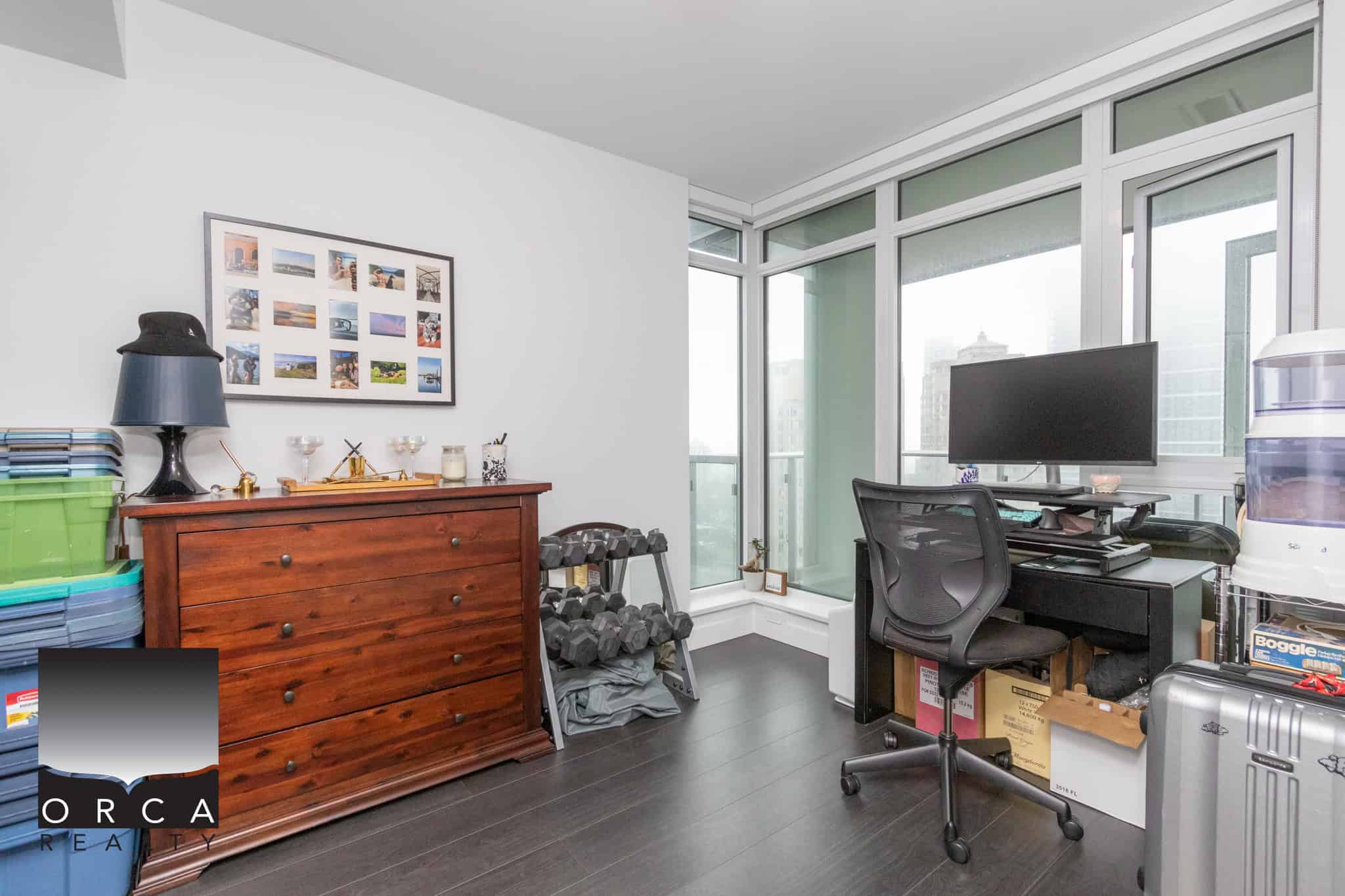 Bright home office with large windows, modern decor, and workspace setup for real estate professionals. Ideal for remote work, showcasing functionality and city views in a Vancouver condo.