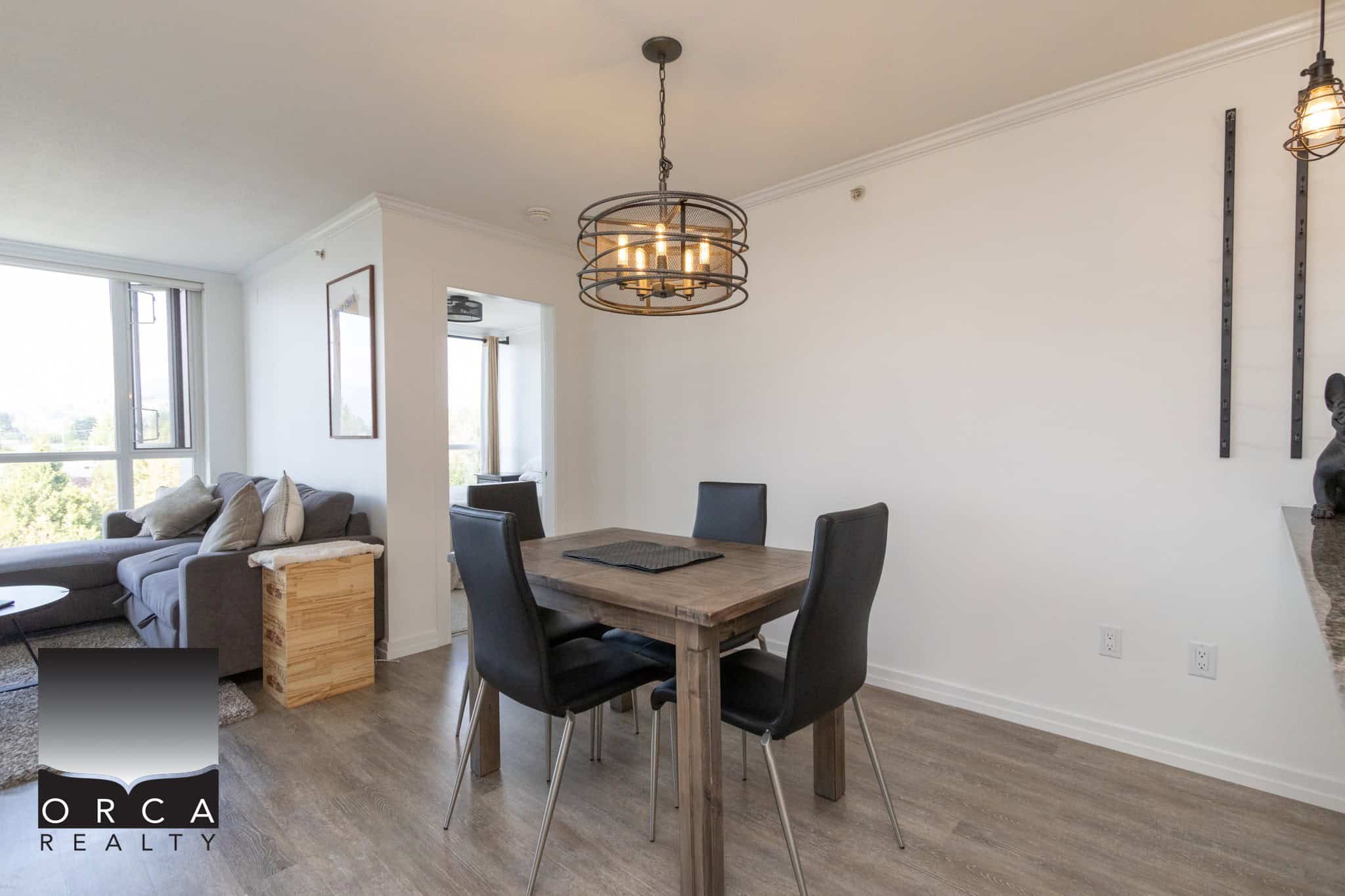Modern urban apartment dining area with hardwood floors, contemporary lighting, and a view of the living room, ideal for homebuyers seeking stylish real estate in Vancouver.