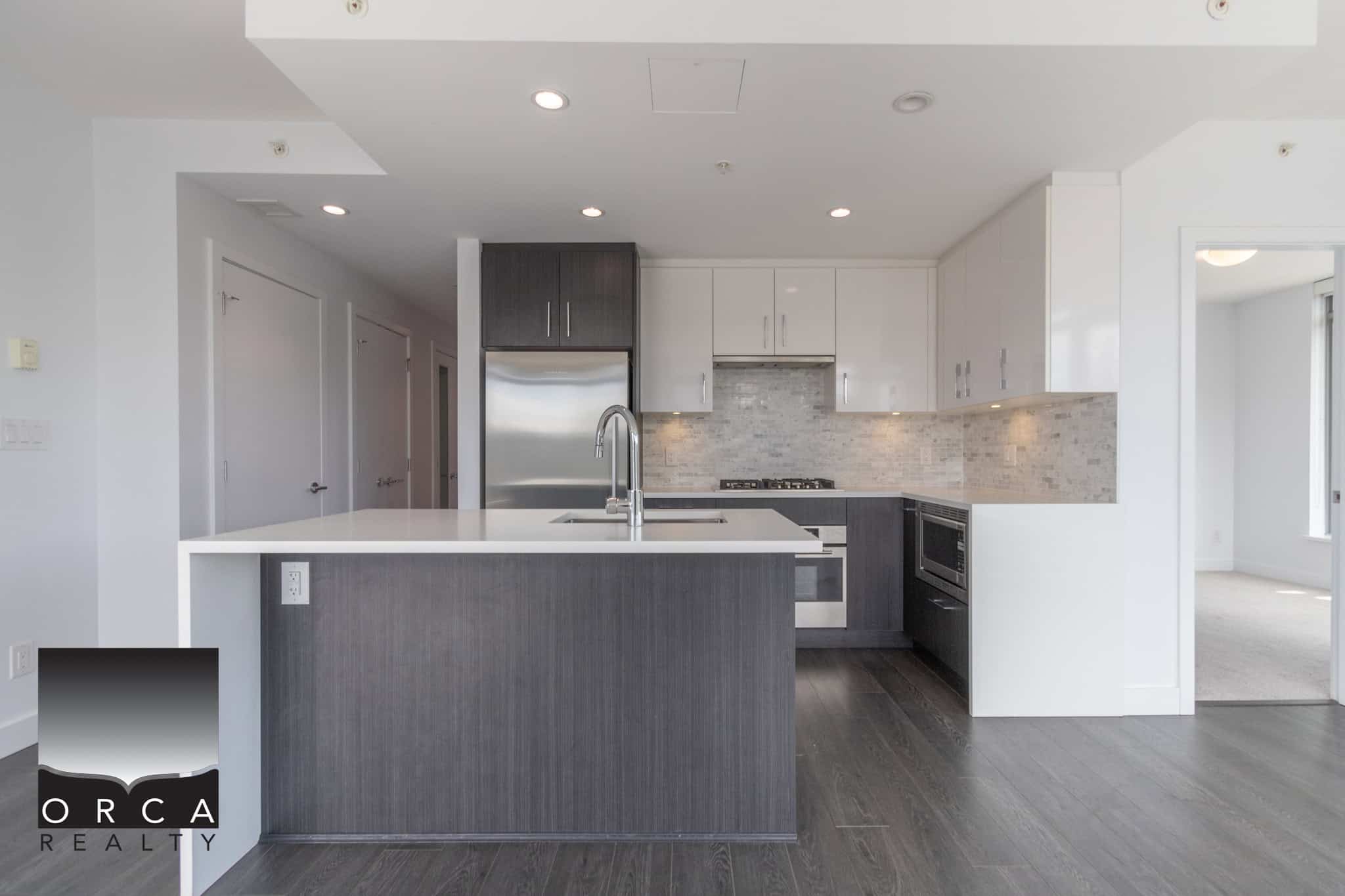 Modern kitchen with sleek white and dark cabinetry, stainless steel appliances, and a spacious island, perfect for contemporary Ottawa real estate properties.