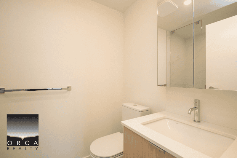 Modern bathroom with white fixtures, minimalist design, and large mirror in a property listed by Orca Realty Inc.