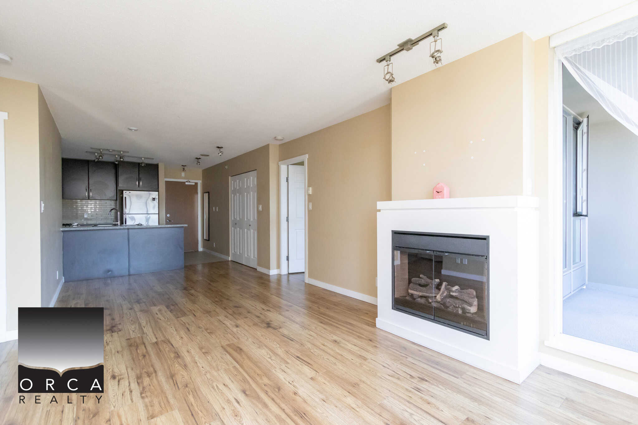 Spacious open-plan living area with hardwood floors, fireplace, and large windows, showcasing modern Vancouver real estate listings by Orca Realty Inc.