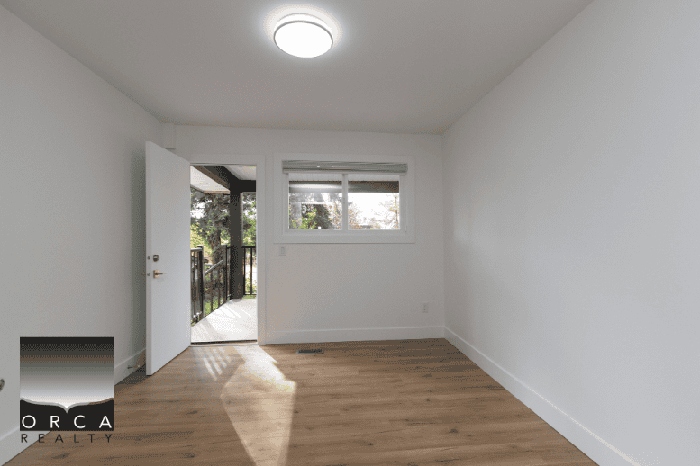 Bright and cozy empty room with a door leading to a balcony, featuring hardwood floors and natural light, perfect for Vancouver waterfront property.