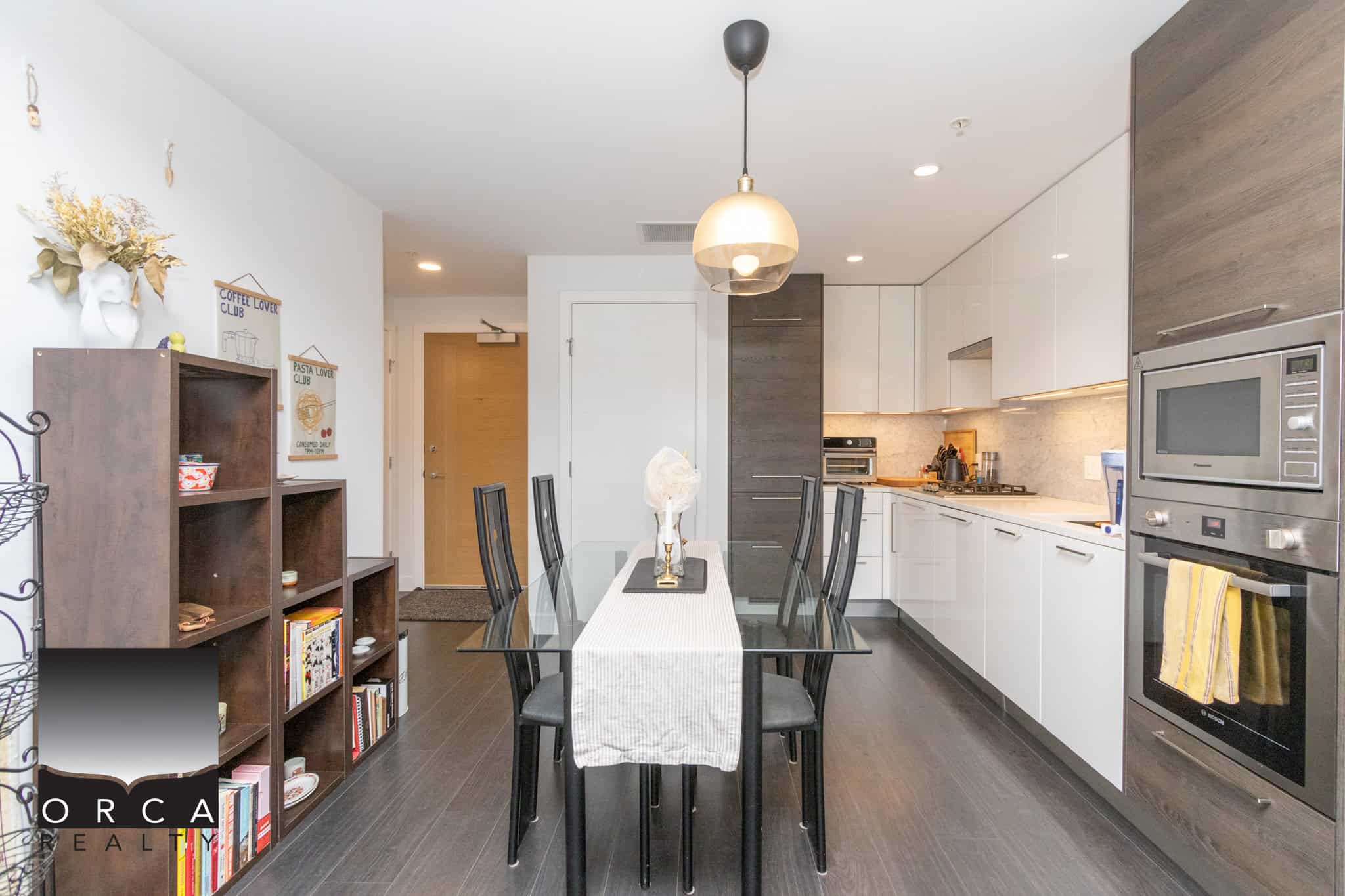 Modern open-concept kitchen with sleek white cabinetry, stainless steel appliances, and dark wood flooring, ideal for contemporary living and entertaining in Vancouver's top real estate markets.