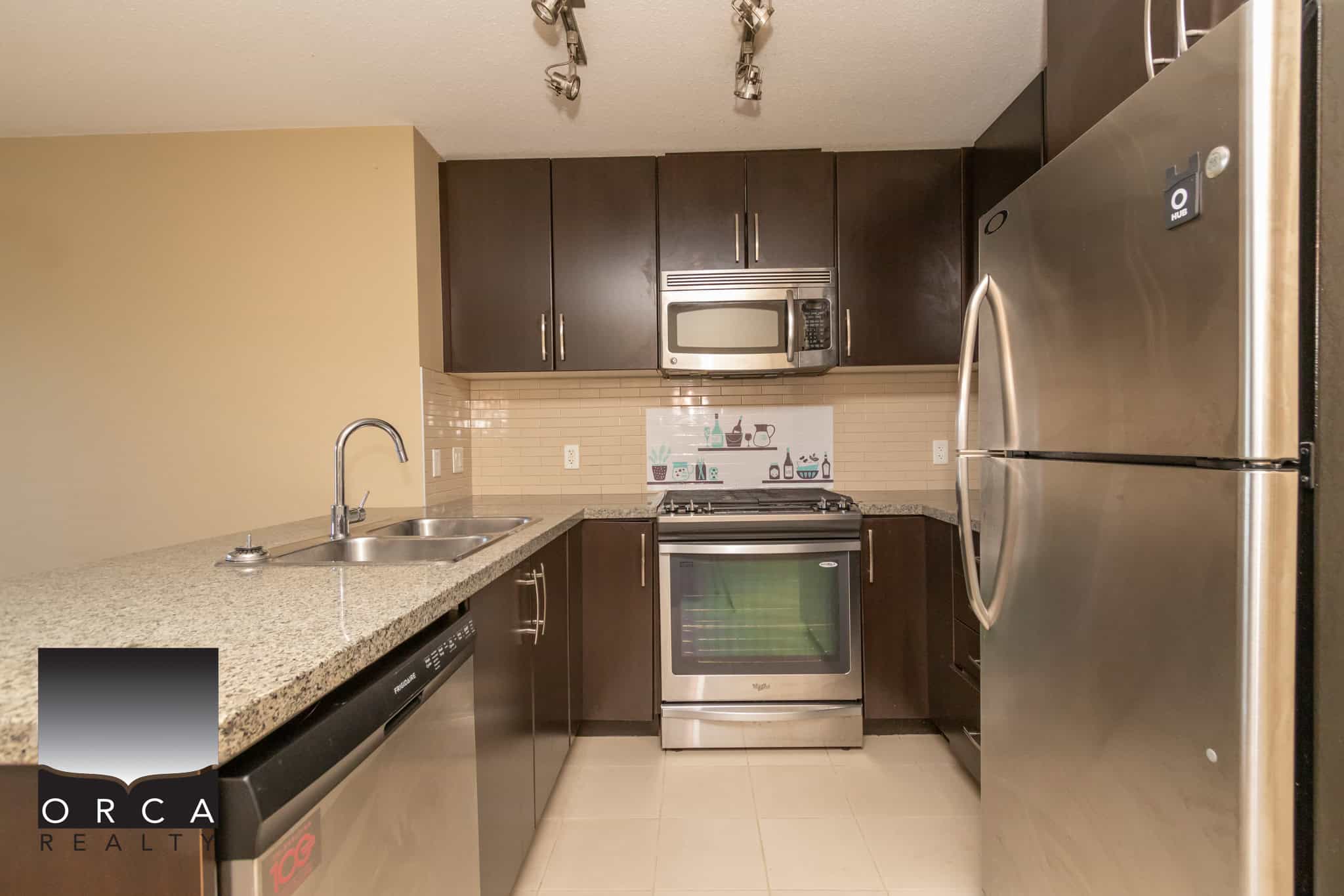 Modern kitchen featuring stainless steel appliances, dark wood cabinets, granite countertops, and beige tile backsplash, ideal for Vancouver real estate listings.