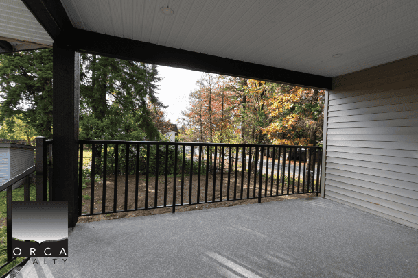 Spacious balcony with black metal railing overlooking lush green trees and autumn foliage, perfect for relaxing outdoor living and enjoying scenic views in Vancouver.
