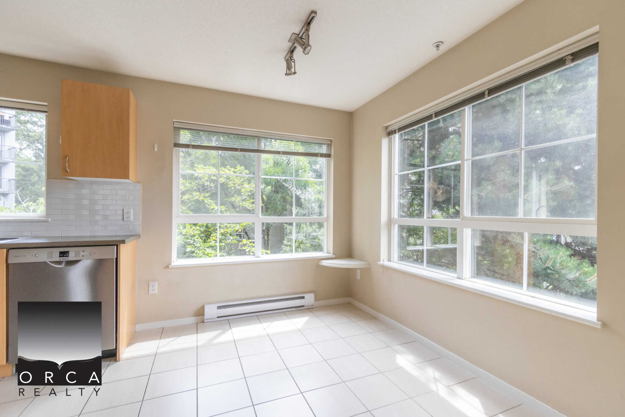 Bright, spacious kitchen with large windows, natural light, white tiled flooring, and modern appliances, perfect for Vancouver real estate buyers.