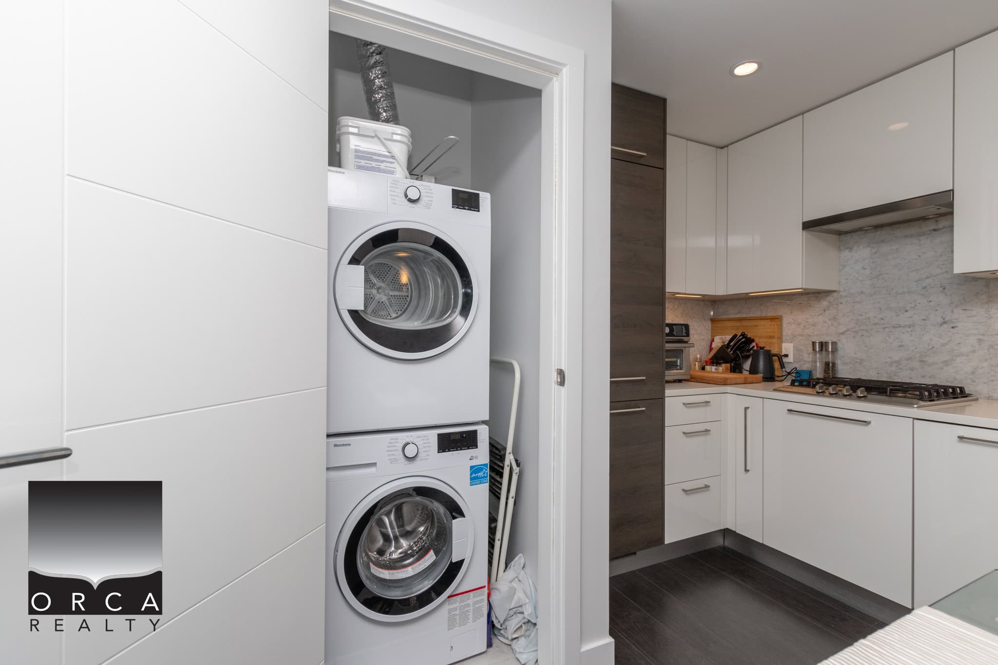 Stacked washer and dryer in a modern laundry area within a kitchen, showcasing functional and stylish home amenities.