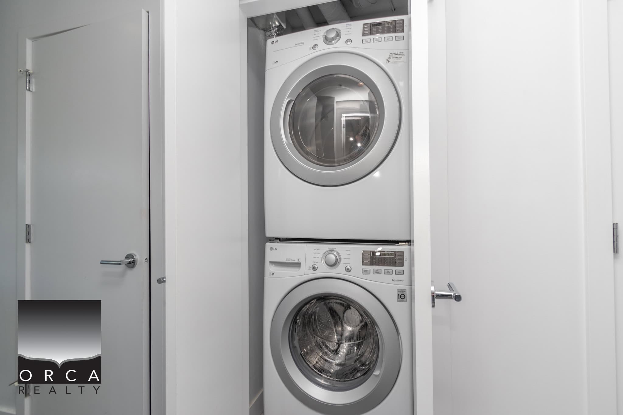 Stacked white front-loading washer and dryer in a modern laundry closet, showcasing convenient appliance storage for Vancouver-area homes.