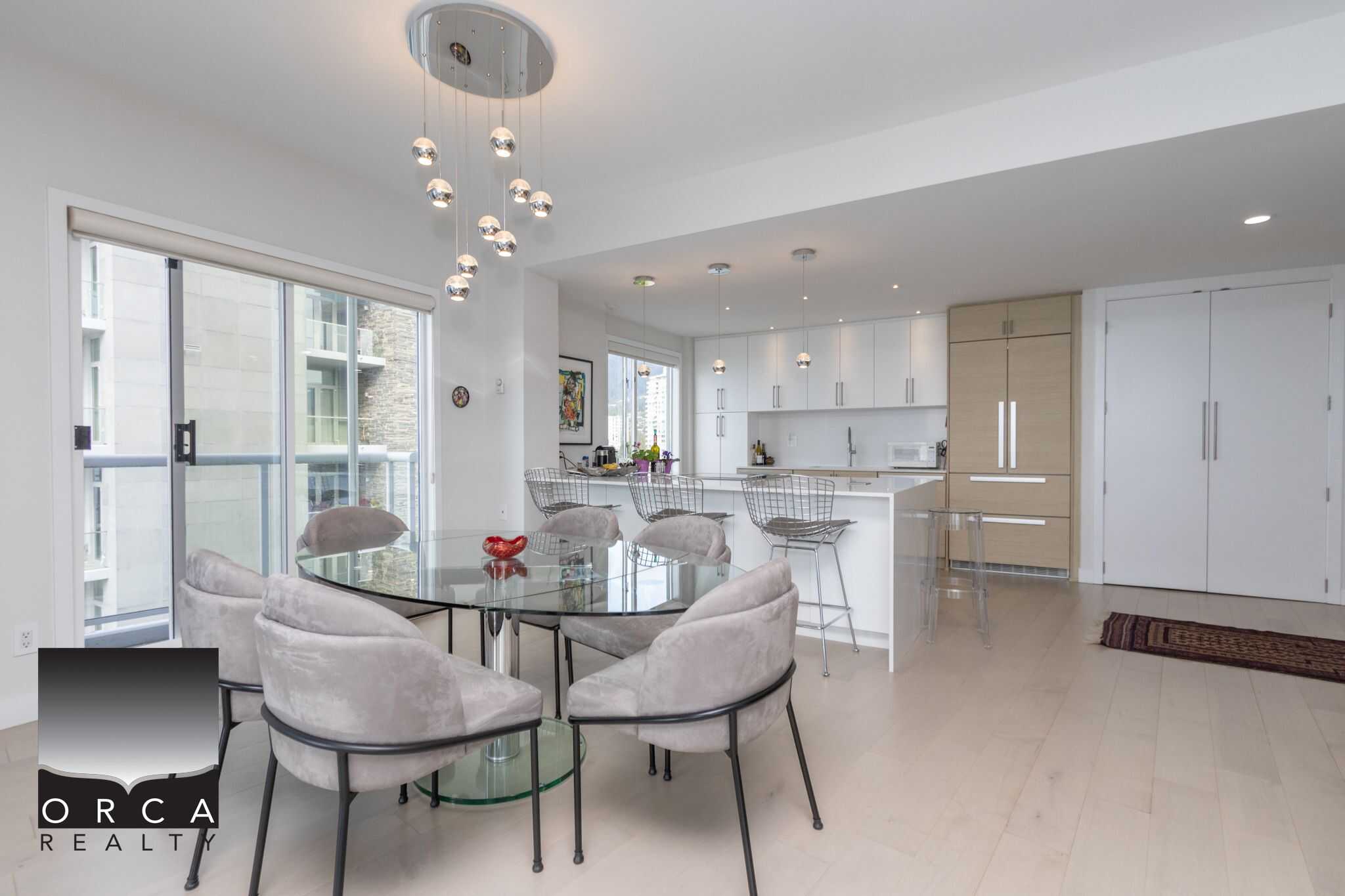 Modern open-concept kitchen and dining area with stylish lighting, light wood flooring, and contemporary furnishings, ideal for Vancouver and BC real estate enthusiasts.