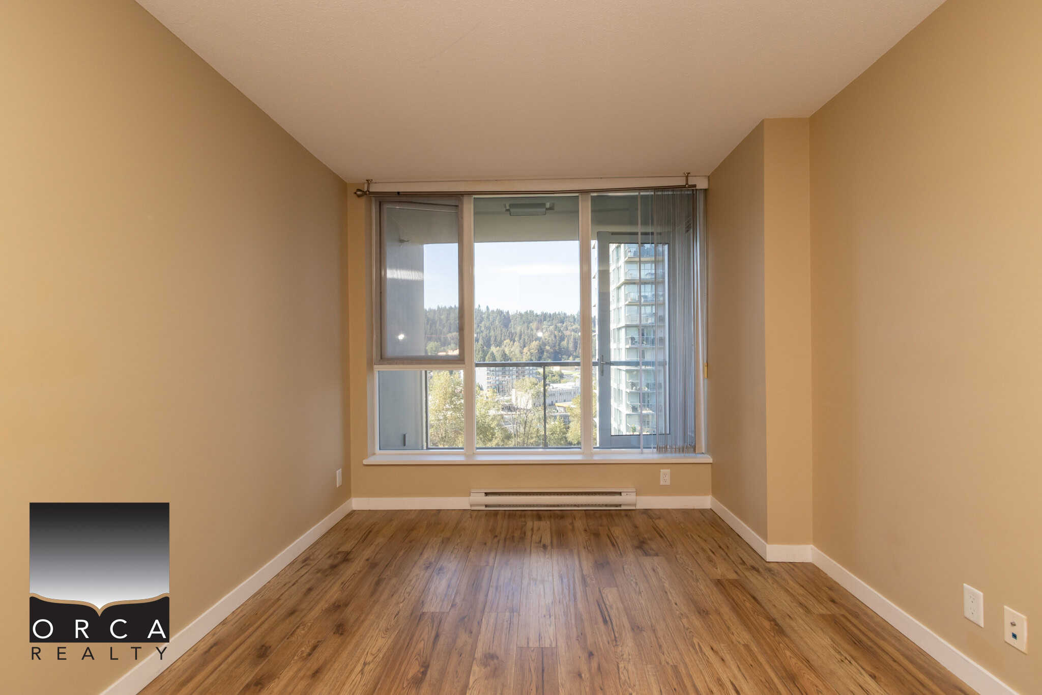 Bright, spacious apartment interior with large window, hardwood floors, and city views, perfect for Vancouver real estate buyers and investors.