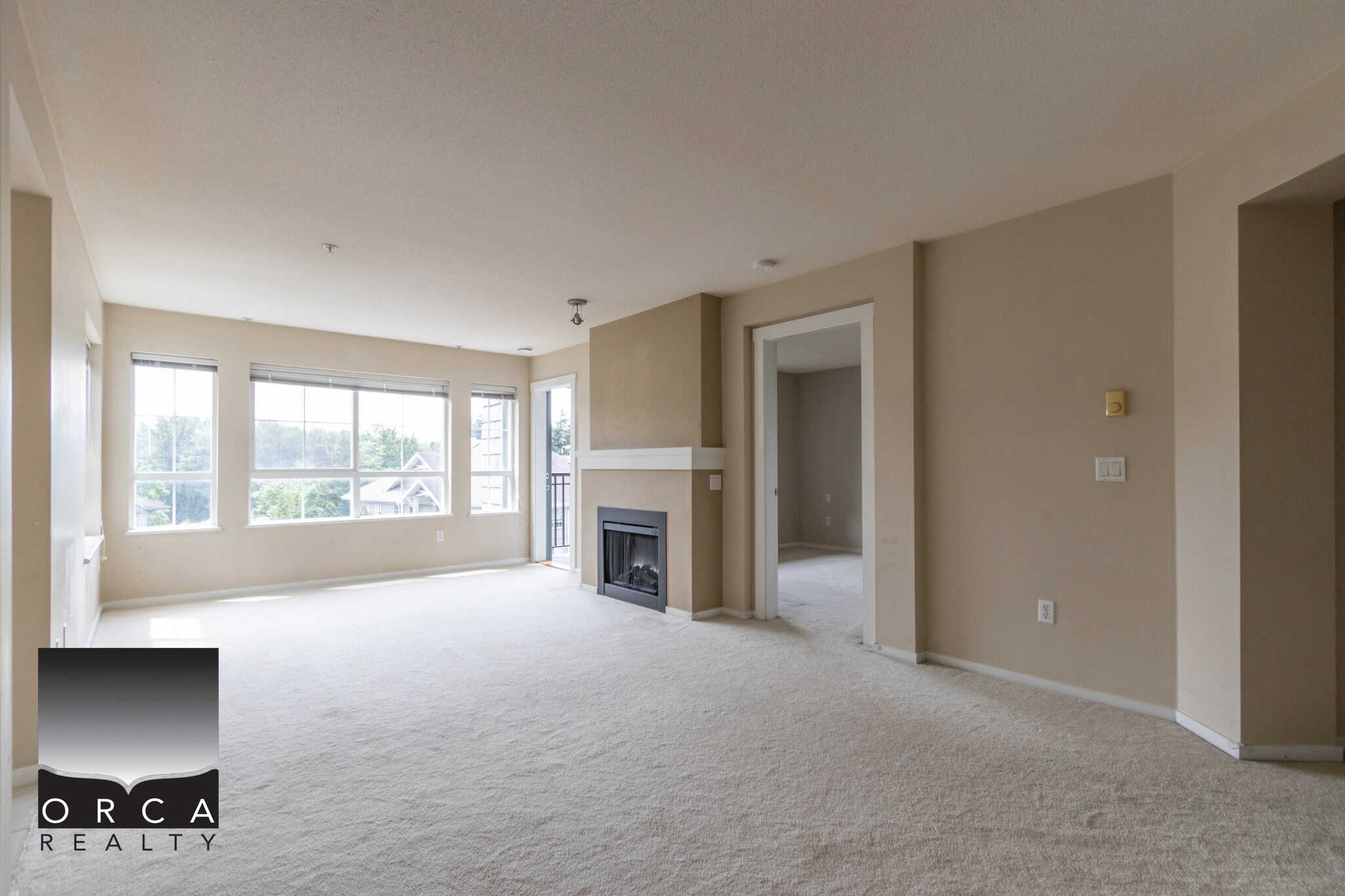 Bright and spacious living room in a Vancouver-area home with large windows, a fireplace, and neutral decor, showcasing desirable features in real estate listings by Orca Realty Inc.