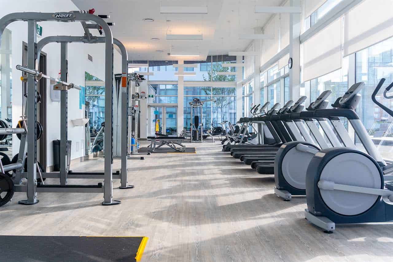 Modern indoor gym with cardio equipment, treadmills, and weight machines at Orca Realty Inc. offering fitness amenities in a bright, spacious setting.