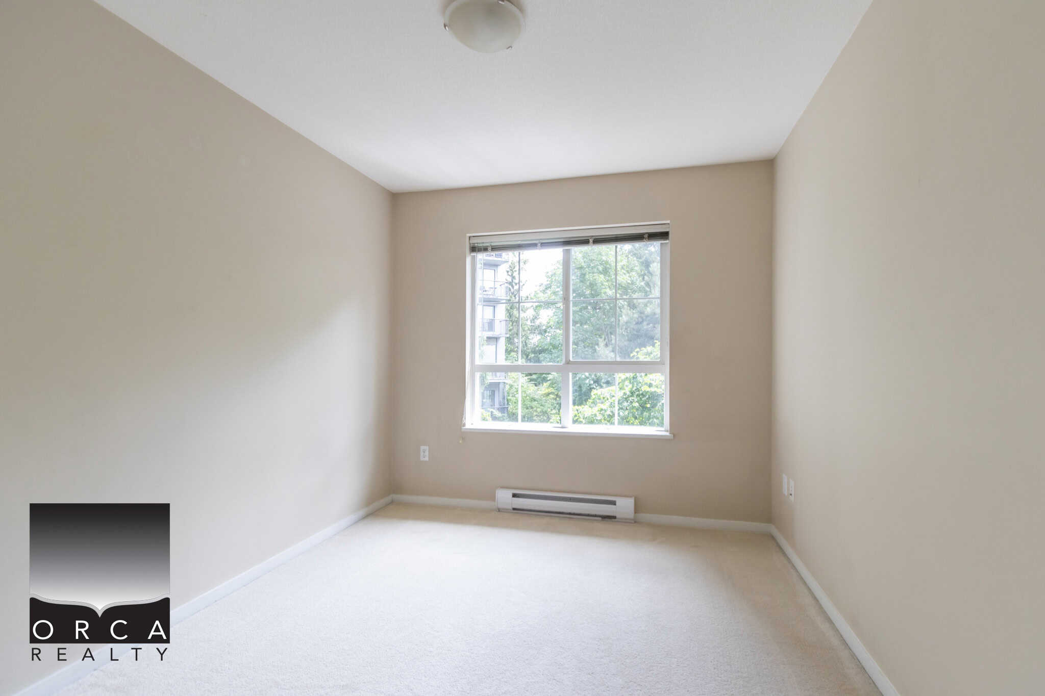 Bright empty room with large window showcasing greenery, neutral wall colour, and soft carpet flooring - ideal for Vancouver or Metro Vancouver real estate listings.