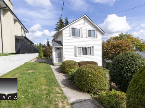 Charming white two-storey home with manicured front yard and lush greenery, located in a desirable neighbourhood, ideal for buyers seeking a cozy residence and investment property in Vancouver.