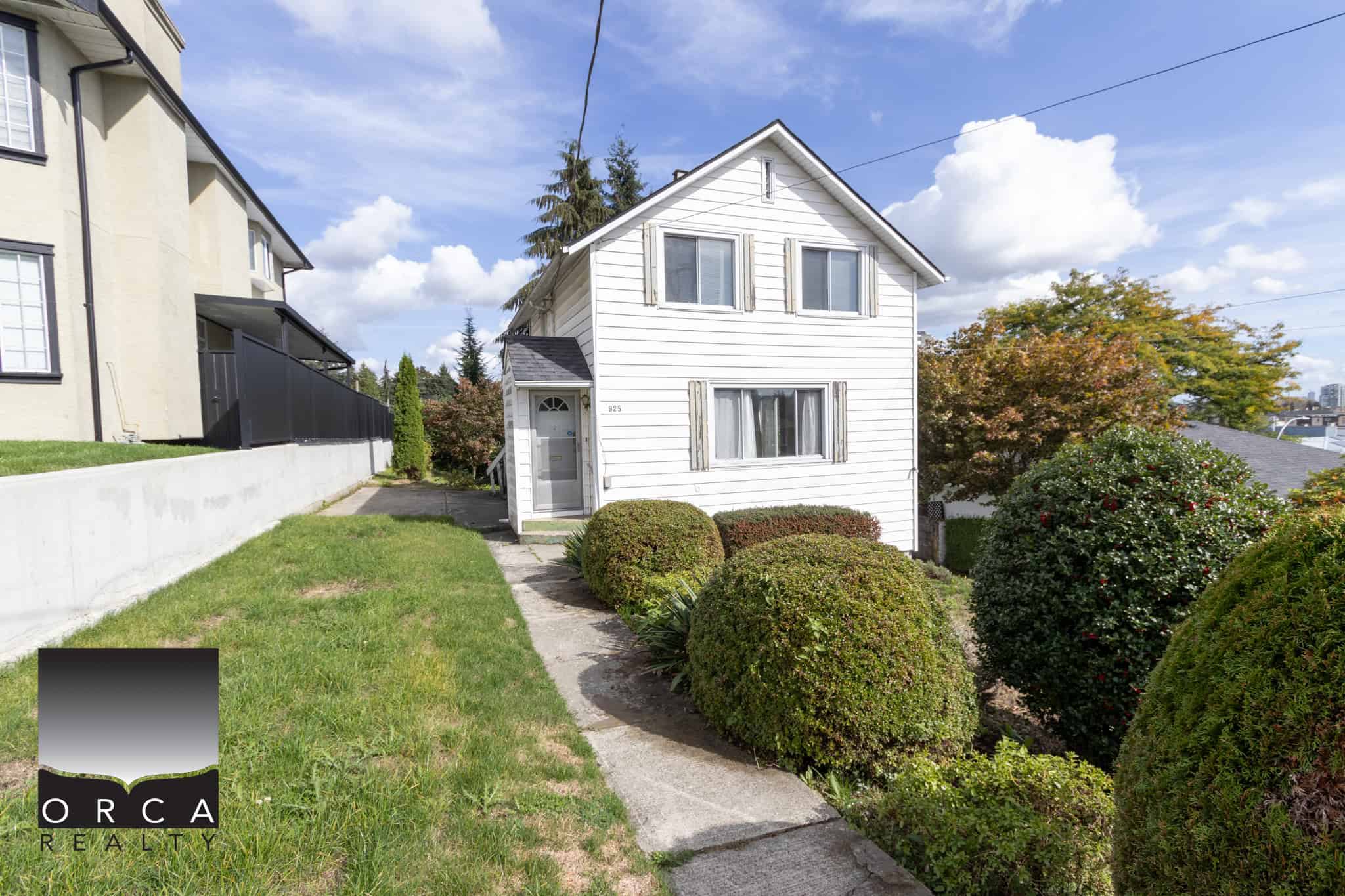 Charming white two-storey home with manicured front yard and lush greenery, located in a desirable neighbourhood, ideal for buyers seeking a cozy residence and investment property in Vancouver.