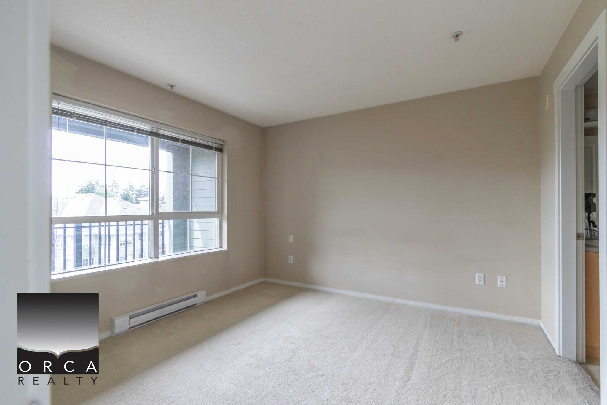 Bright living room with large window, neutral walls, and carpet flooring, ideal for Vancouver area real estate listings.
