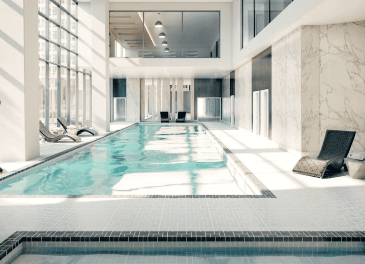 Luxurious indoor swimming pool at a modern condominium with natural sunlight, sleek design, and comfortable lounge chairs, ideal for relaxing and wellness in Vancouver real estate.