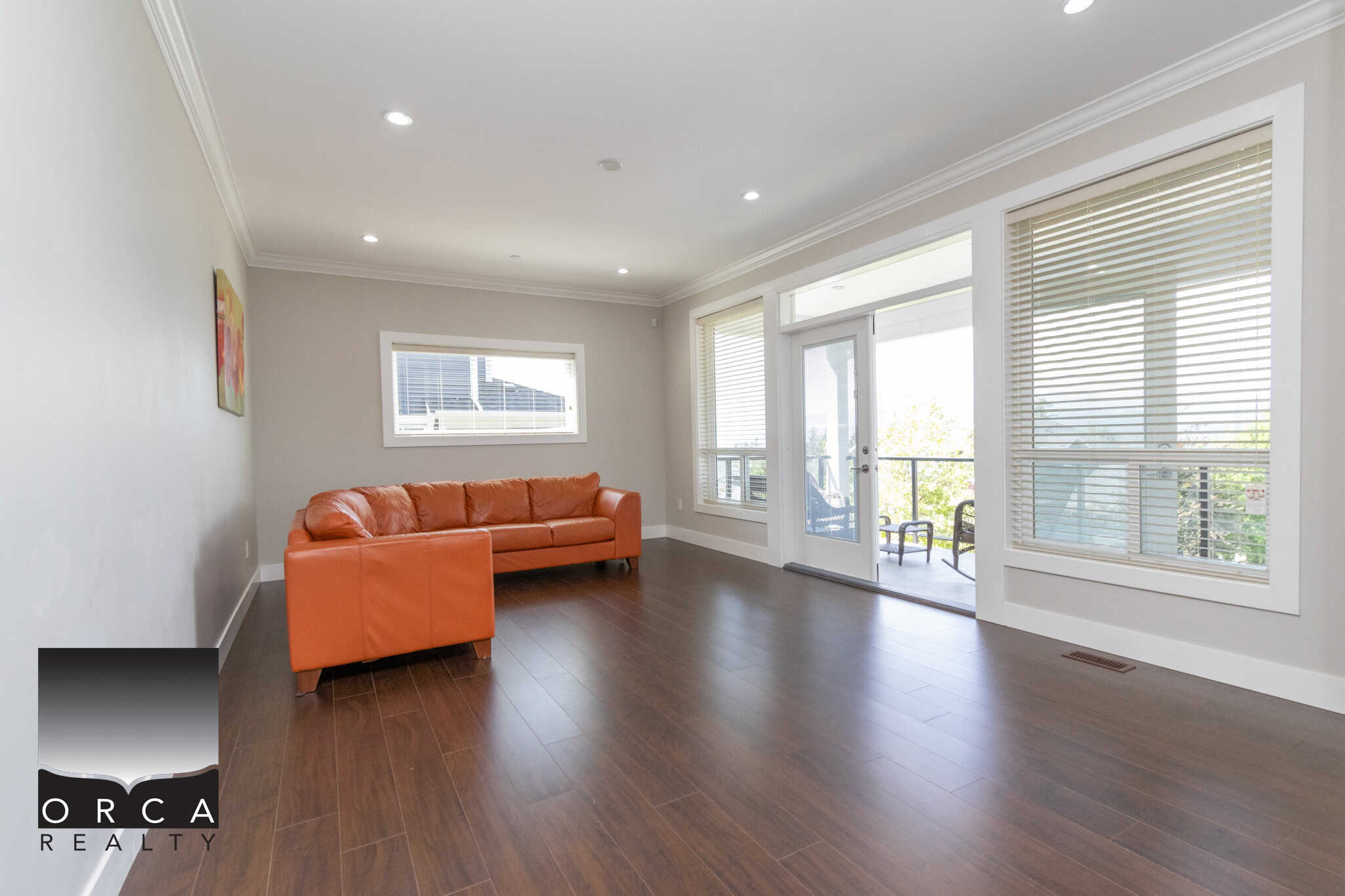 Spacious living room with large windows, hardwood floors, and modern decor, showcasing the comfort and elegance of Orca Realty Inc. properties.