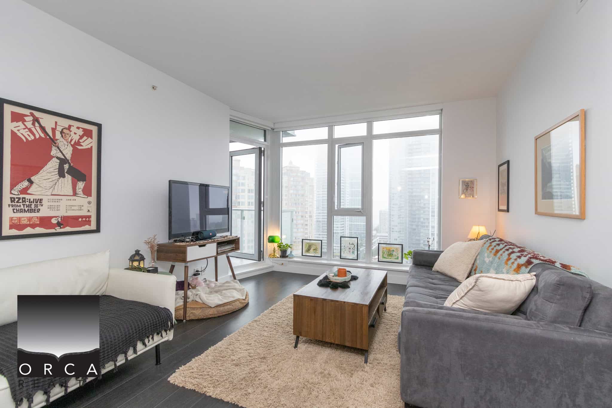 Modern downtown Vancouver condo living room with large windows, city views, comfortable grey sofa, and contemporary decor, perfect for real estate buyers seeking urban condos.