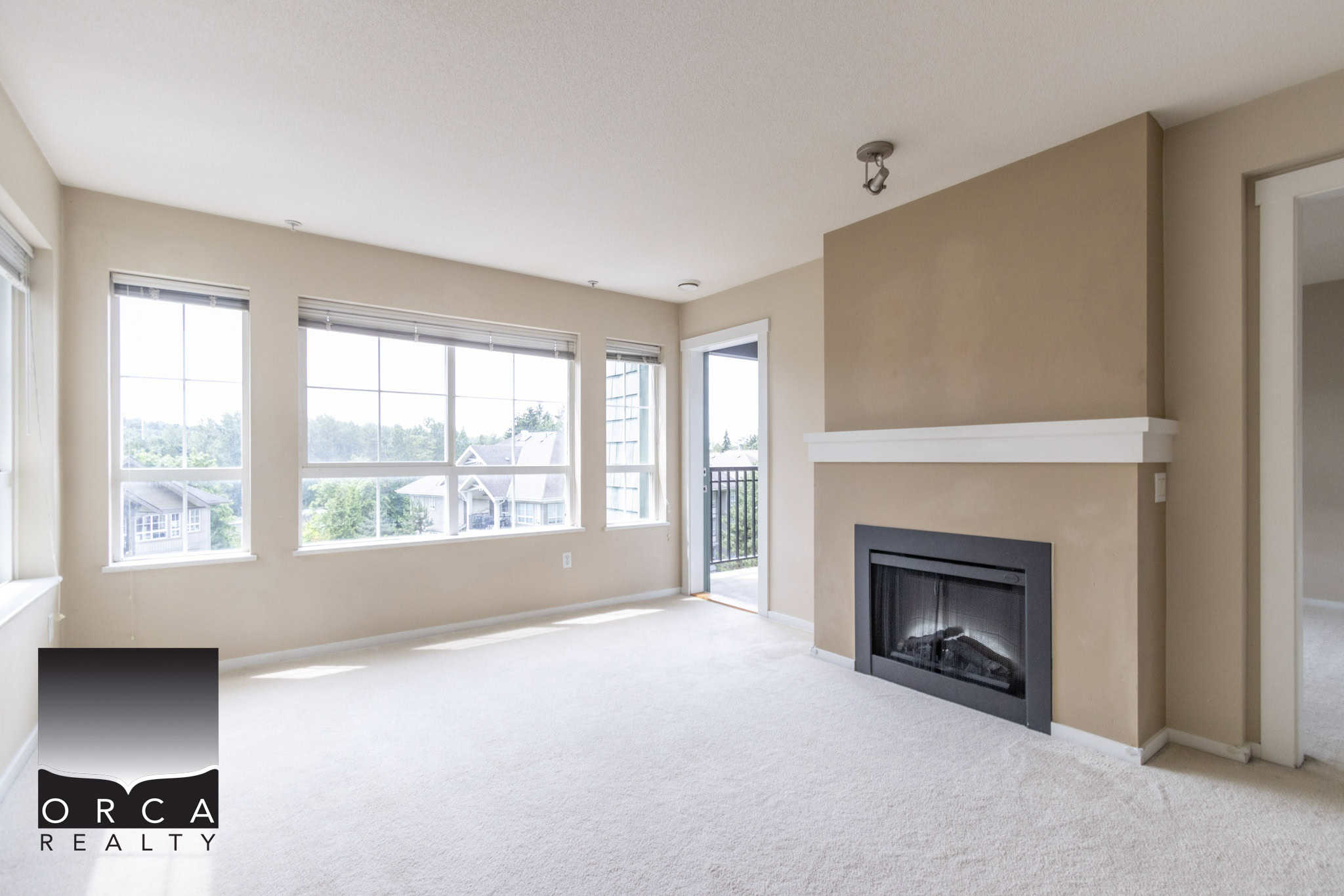 Bright living room with large windows and a cozy fireplace, showcasing a spacious and inviting home interior perfect for family living and entertaining.