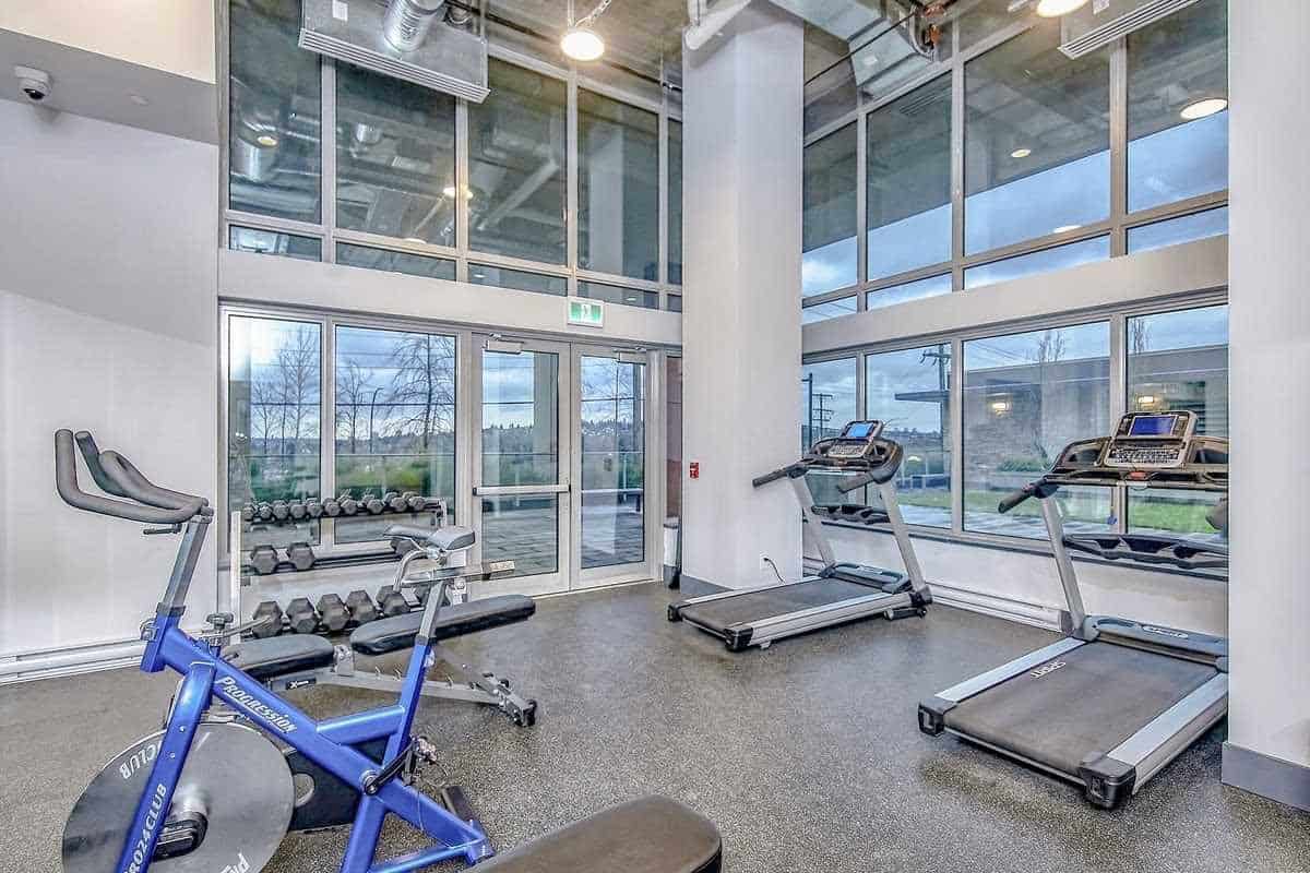 Modern fitness room with cardio equipment and large windows in Orca Realty Inc. commercial property. Perfect for tenants seeking in-house gym amenities and a healthy lifestyle.