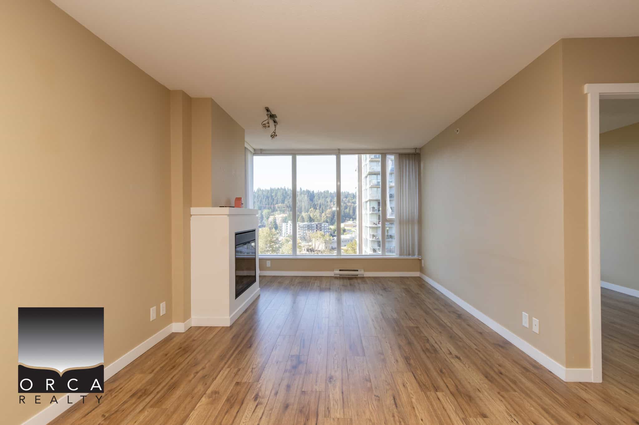 Spacious living room in a modern Vancouver apartment with large windows, hardwood flooring, and a cozy fireplace, offering stunning city views and a bright open-concept layout.