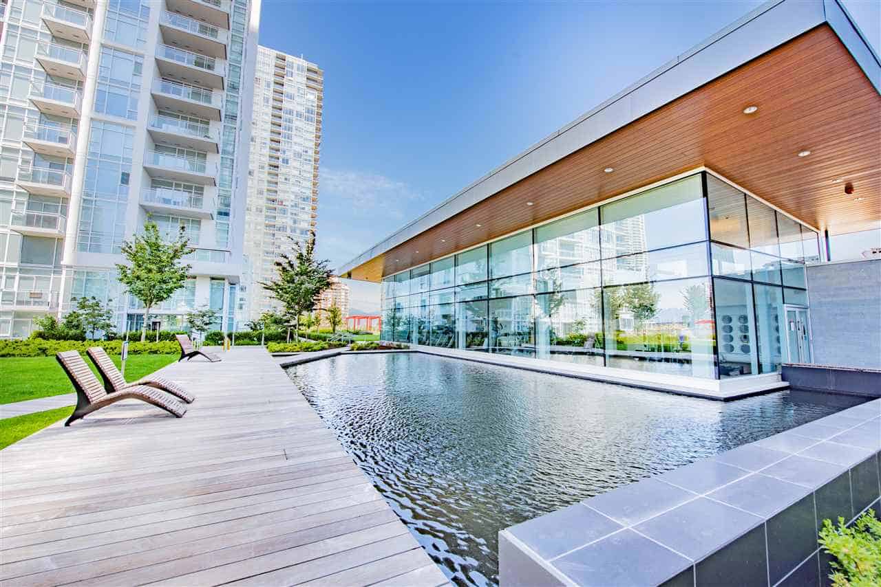 Modern waterfront condo building with outdoor pool and lounge area in downtown Vancouver, BC. Luxurious real estate listings with premium amenities in a vibrant urban setting.