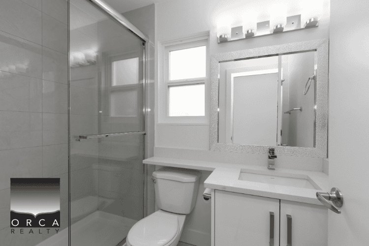 Modern bathroom with walk-in shower, white cabinetry, and bright natural light, ideal for Vancouver real estate listings.